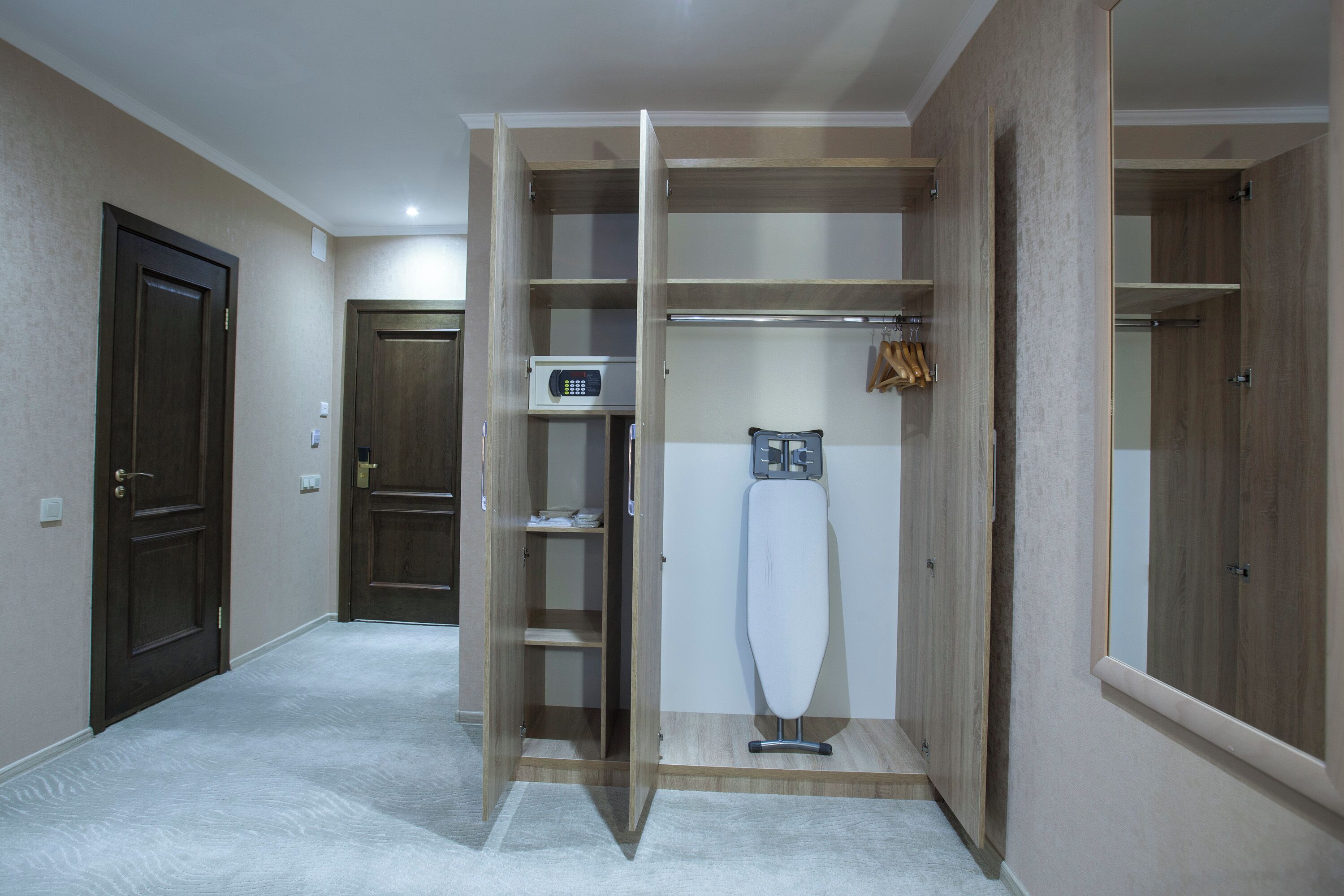 A hotel room with a wardrobe, a microwave, and a hanging garment rack.