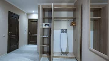 A hotel room with a wardrobe, a microwave, and a hanging garment rack.