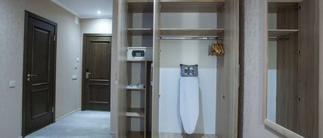 A hotel room with a wardrobe, a microwave, and a hanging garment rack.