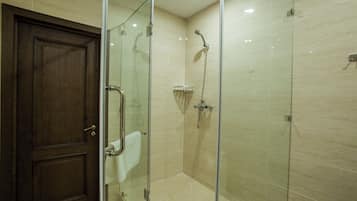 A glass-enclosed shower with a handheld showerhead and a wall-mounted faucet.