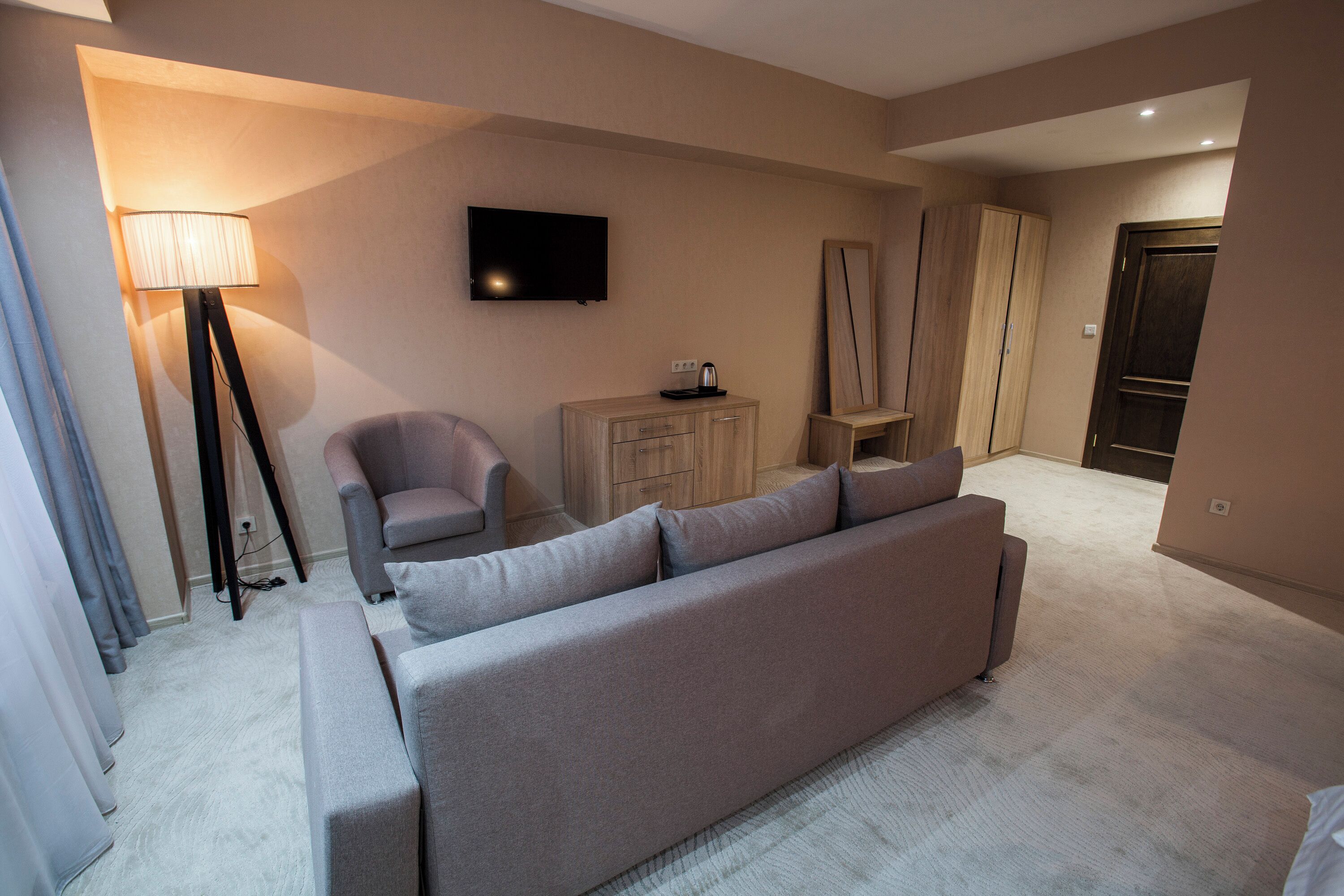 Una sala de estar moderna con sofá, sillón, televisor de pantalla plana y lámpara.