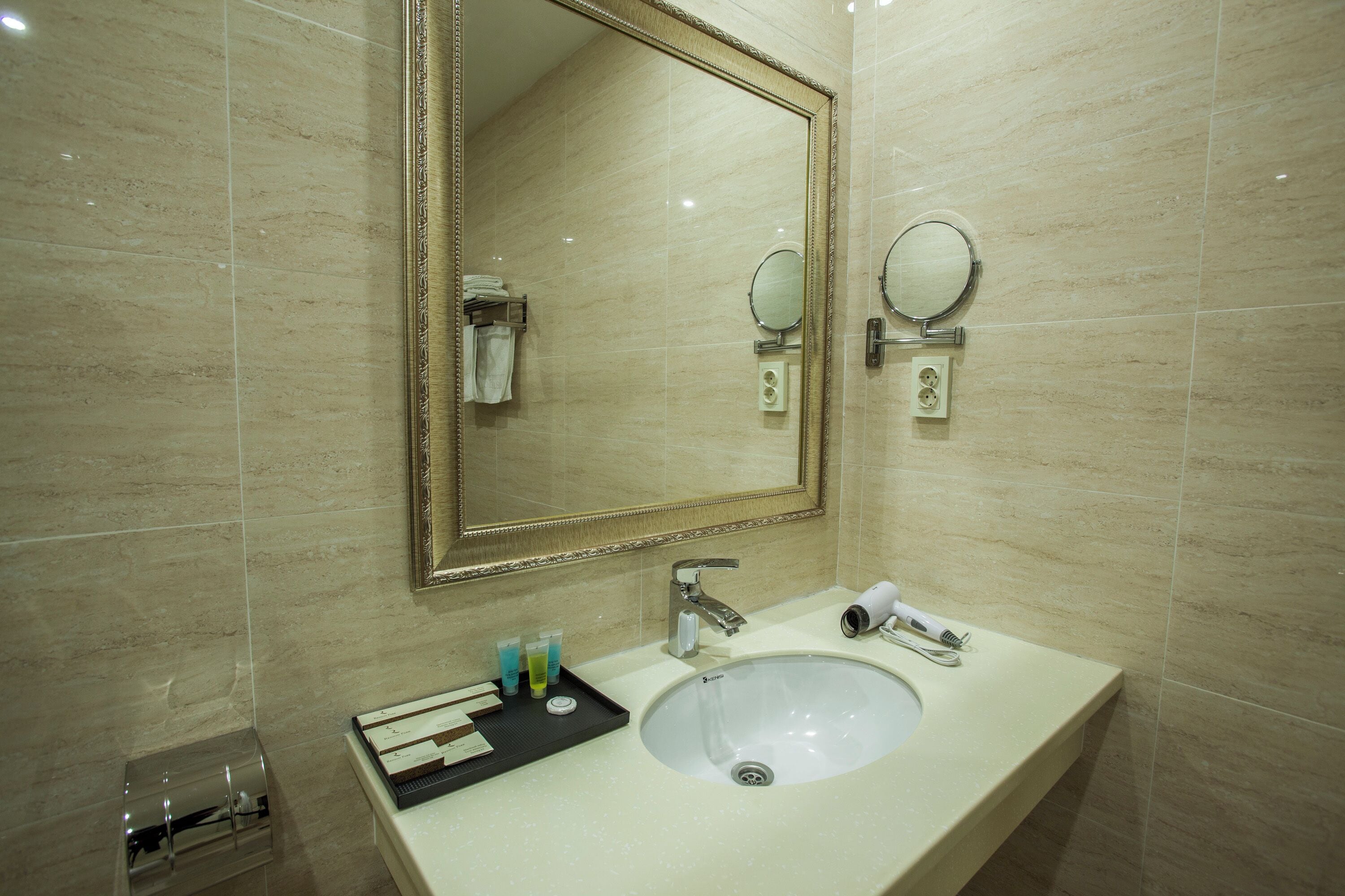 A bathroom with a large mirror, a sink, and a towel rack.