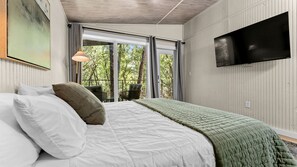 Une chambre à coucher avec un lit, une télévision et une fenêtre donnant sur des arbres.