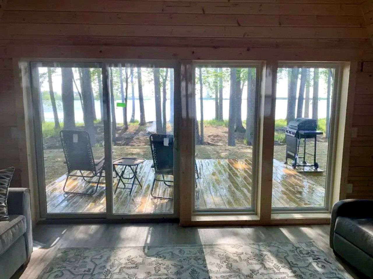 Une pièce dotée d’une grande porte-fenêtre coulissante qui donne sur une terrasse extérieure aménagée avec des chaises et un barbecue.