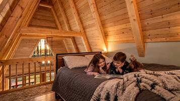 A high-ceilinged wooden room with a bed, a window, and a view of the outdoors.