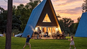 A modern, triangular-shaped building with a large glass window and a patio area.