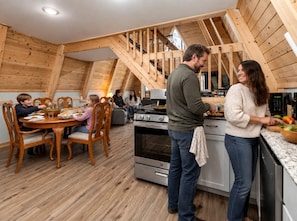 A cozy kitchen with wooden beams, a dining area with a round table, and a staircase.
