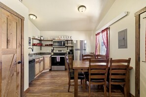 Eine kompakte Küche mit Mikrowelle, Herd und Kühlschrank, einem Holztisch mit Stühlen und einem Fenster mit Vorhängen.
