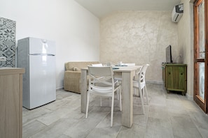 Eine kleine Küche mit Kühlschrank, Esstisch, Stühlen und einem Schrank.