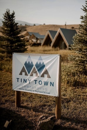 Un panneau indiquant l’emplacement du camping « Tiny Town », avec une illustration de montagne et du texte.