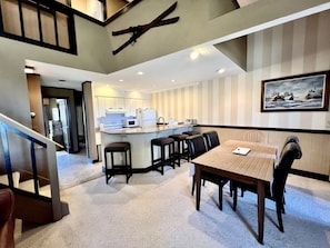 A hotel lobby with a dining area, a kitchen, and a staircase. - Mountain Cabin Great for a Family Retreat in Vermont (Stratton)