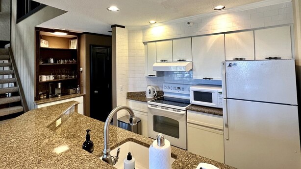 A modern kitchen with granite countertops, stainless steel appliances, and white cabinetry. - Mountain Cabin Great for a Family Retreat in Vermont (Stratton)