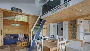 A modern interior with a wooden dining area, a staircase, and a kitchen with glass cabinets.