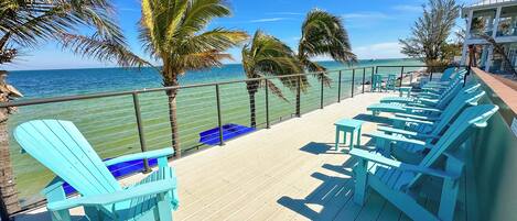 A deck with blue chairs and a view of the ocean.