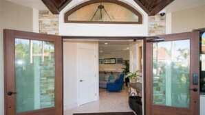 A modern entrance with glass doors, a stone wall, a blue sofa, and a ceiling light. - The Rod and Reel Resort-Grand Suite 6 (Anna Maria)