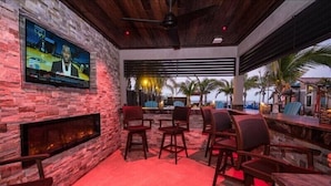A bar area with stone walls, a flat-screen TV, and outdoor seating. - The Rod and Reel Resort-Grand Suite 6 (Anna Maria)