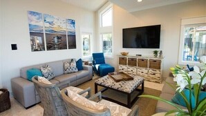 A living room with a sofa, chairs, a coffee table, a TV, and artwork on the wall. - The Rod and Reel Resort-Grand Suite 8 (Anna Maria)