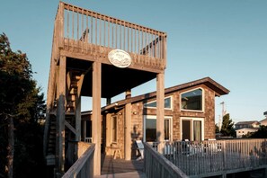 A wooden structure with a balcony, a sign reading 'HYGE,' and a modern building with large windows. - Incredible Unique Beach House with Stunning Sea Views for an Unforgettable Coastal Escape in Avon, North Carolina (Avon)