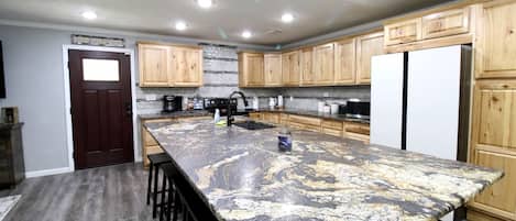 Una cocina con armarios de madera, encimera de granito y refrigerador de acero inoxidable.