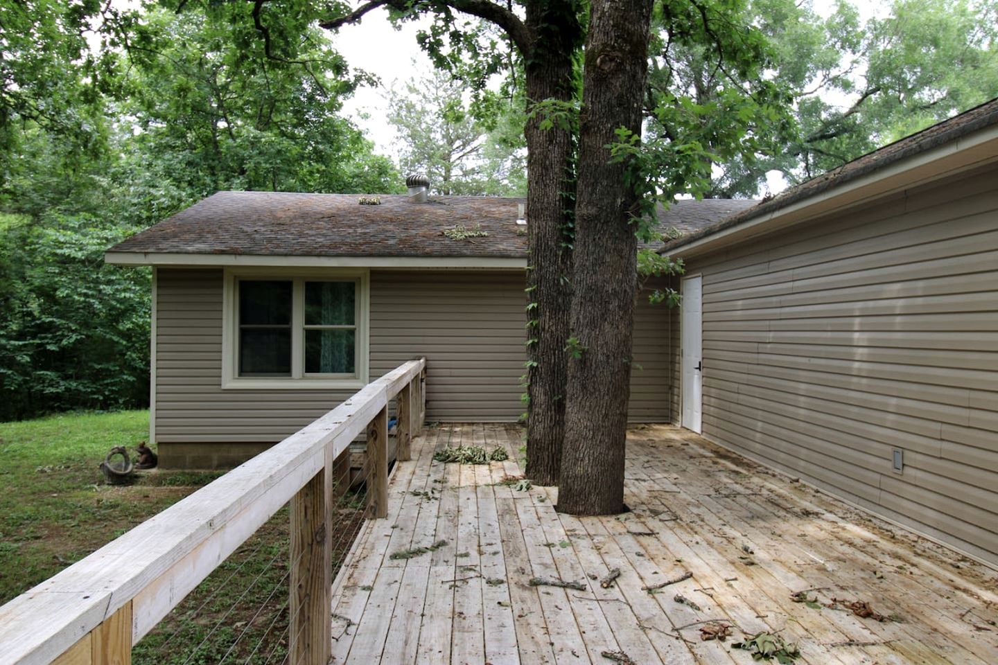 A house with a wooden deck, a window, and a tree.