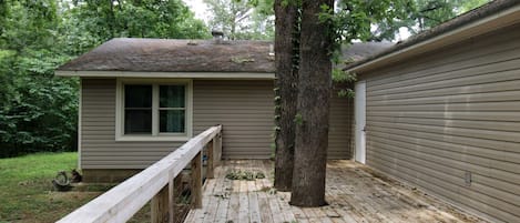 A house with a wooden deck, a window, and a tree.