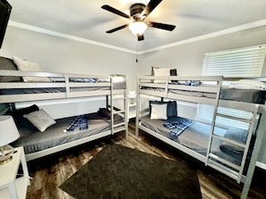 A room with bunk beds, a ceiling fan, and a window with blinds. - Charming Cottage Nestled Amidst Trees in Hot Springs, Arkansas (Hot Springs)