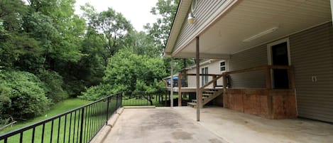 A covered outdoor area with a concrete floor, a wooden staircase, and a metal railing.