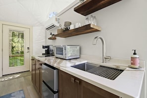 Eine moderne Küche mit einem eingebauten Geschirrspüler, einer Kaffeemaschine, einem Toaster und einem Spülbecken mit Seifenspender.