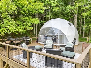 Ein Geodätendutzelt mit einem Moskitonetz-Vorraum, Gartenmöbeln und einem Grill.