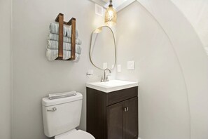 Et moderne badeværelse med toilet, håndvask og håndklædetørrestativ.