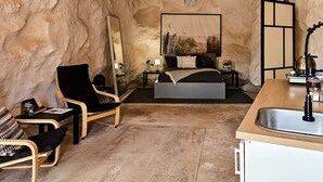 Un dormitorio con cama, mesitas de noche, una silla, un espejo y un lavabo.