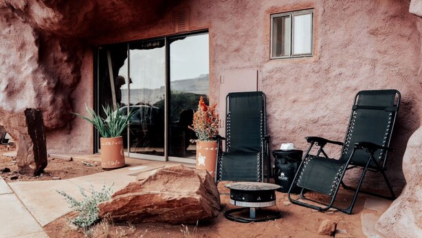 Un área de estar al aire libre con dos sillones, una mesa y plantas en macetas.