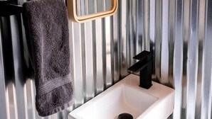 Un baño con un lavamanos blanco, una toalla colgada en la pared y un espejo.