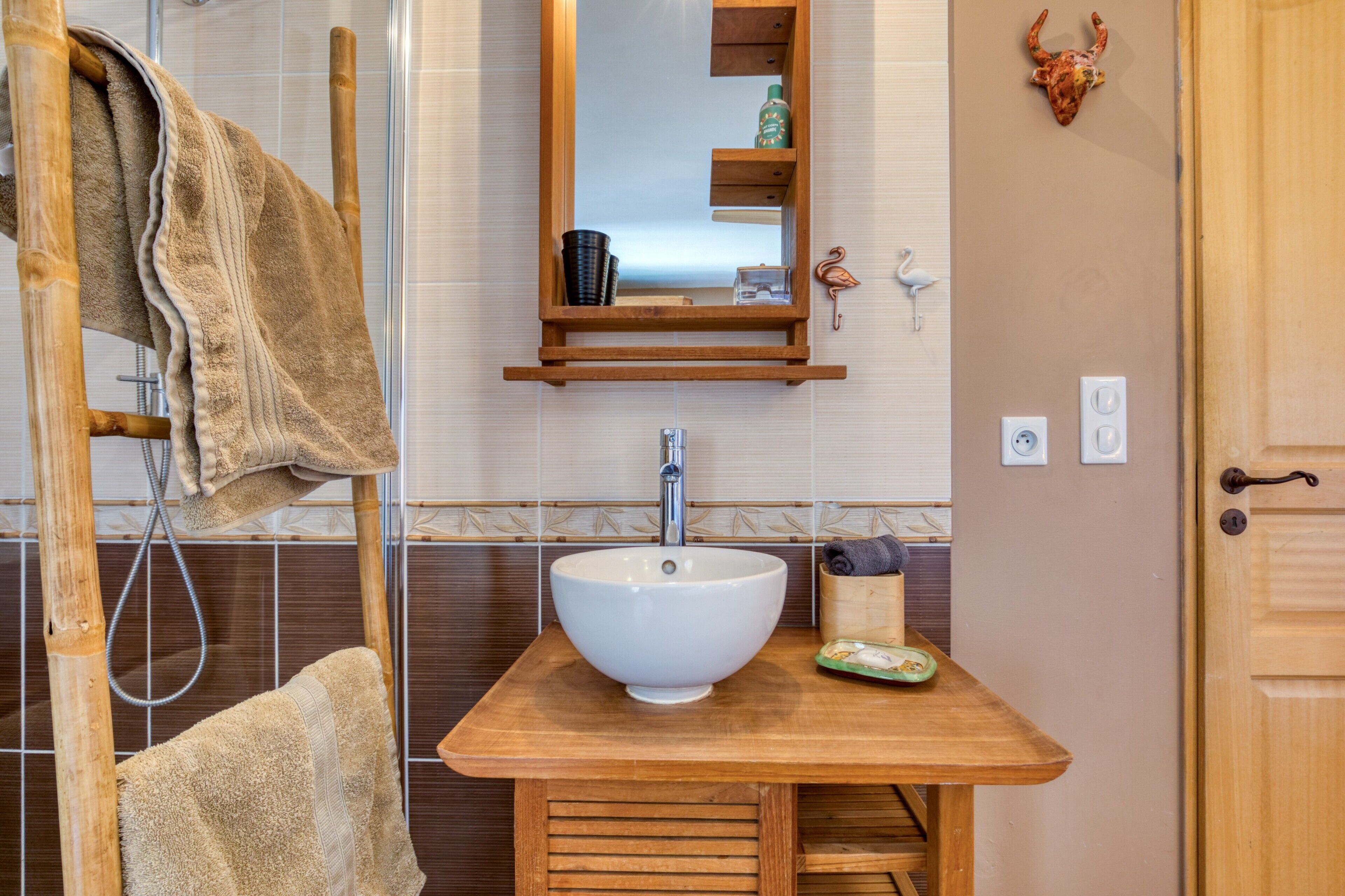 A bathroom with a wooden vanity, a white sink, a towel rack, and a mirror.
