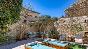 A courtyard with stone walls, a wooden bench, a table with chairs, and two sunbeds. - Guest Room "La Petite Camargue" with Private Pool, Shared Terrace and Wi-Fi (Vauvert)