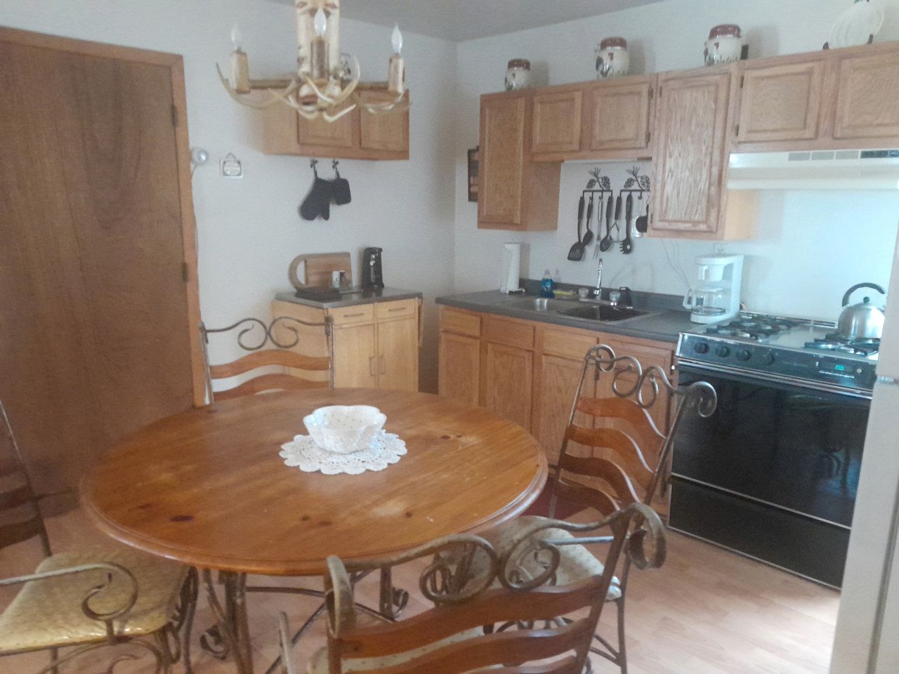 A kitchen with wooden cabinets, a stove, and a dining table with chairs.