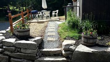 A gravel pathway leading to outdoor seating with a wooden fence and potted plants.