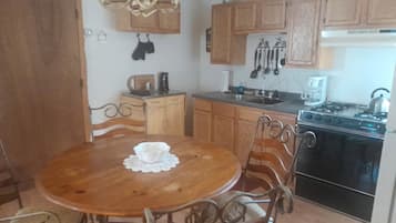 A kitchen with wooden cabinets, a stove, and a dining table with chairs.