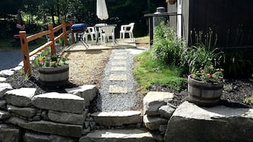 Un sendero de grava que lleva a una zona de estar al aire libre con valla de madera y plantas en macetas.