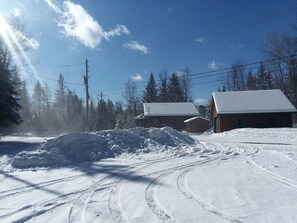 A snow-covered landscape with a pile of snow, a building with a snow-covered roof, and a clear sky.