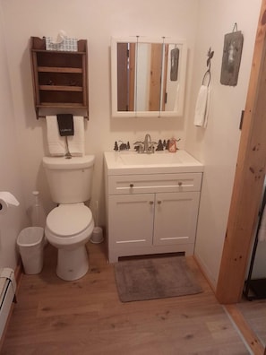 Ein kleines Badezimmer mit Toilette, Waschbecken und einem kleinen Ablagebrett darüber.
