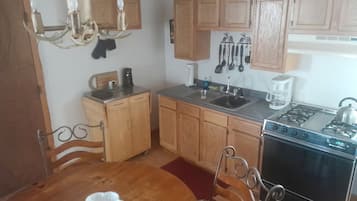 Una cocina con armarios de madera, estufa y una mesa de comedor con sillas.