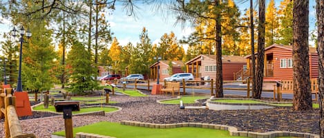 Un campo de minigolf con una cabaña de madera al fondo.