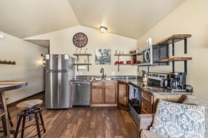 A compact kitchen with a refrigerator, stove, sink, and wooden cabinets. - Delightful Old West Cabin in Island Park, Idaho (Island Park)