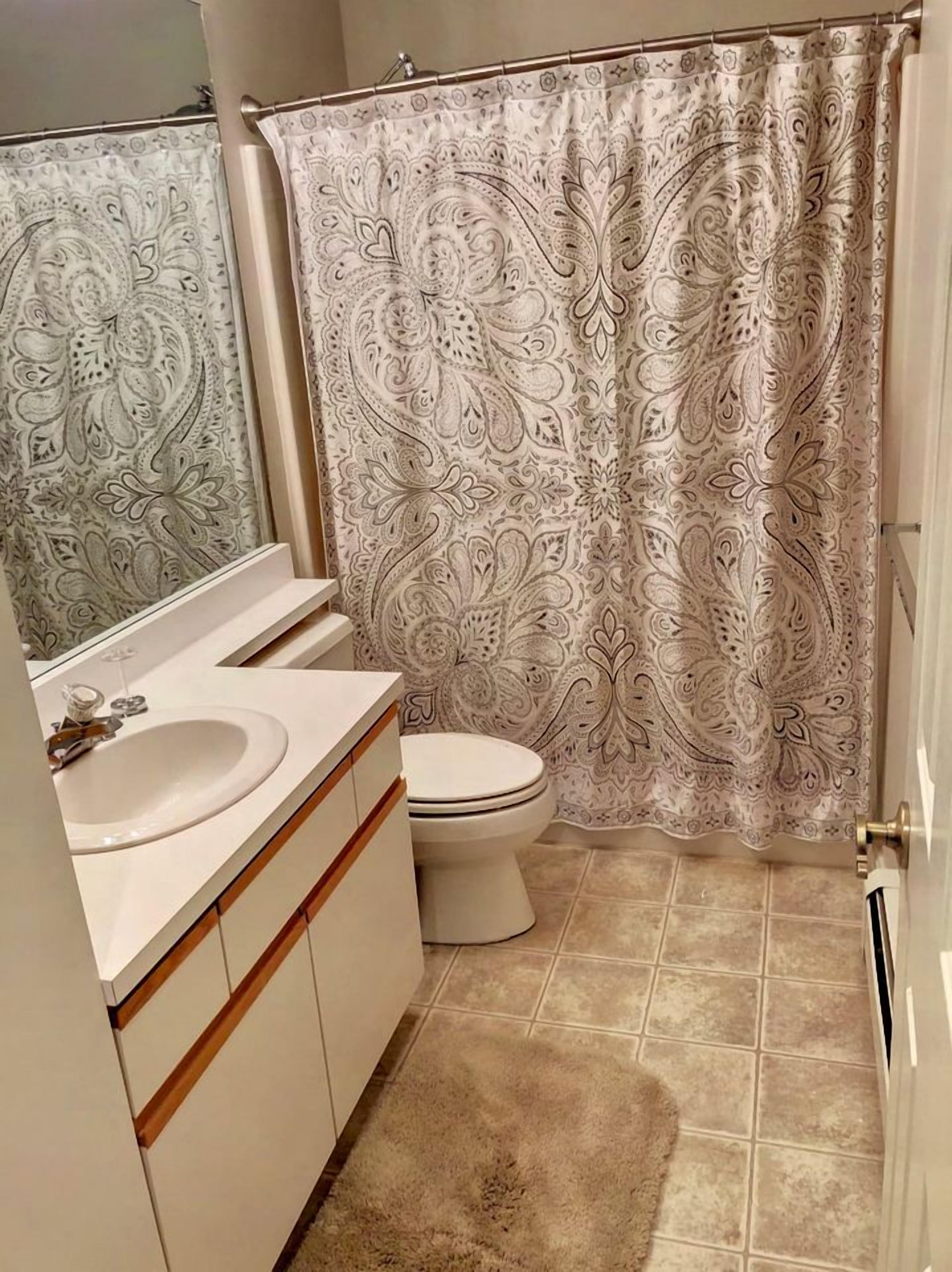 A bathroom with a toilet, sink, and shower curtain.