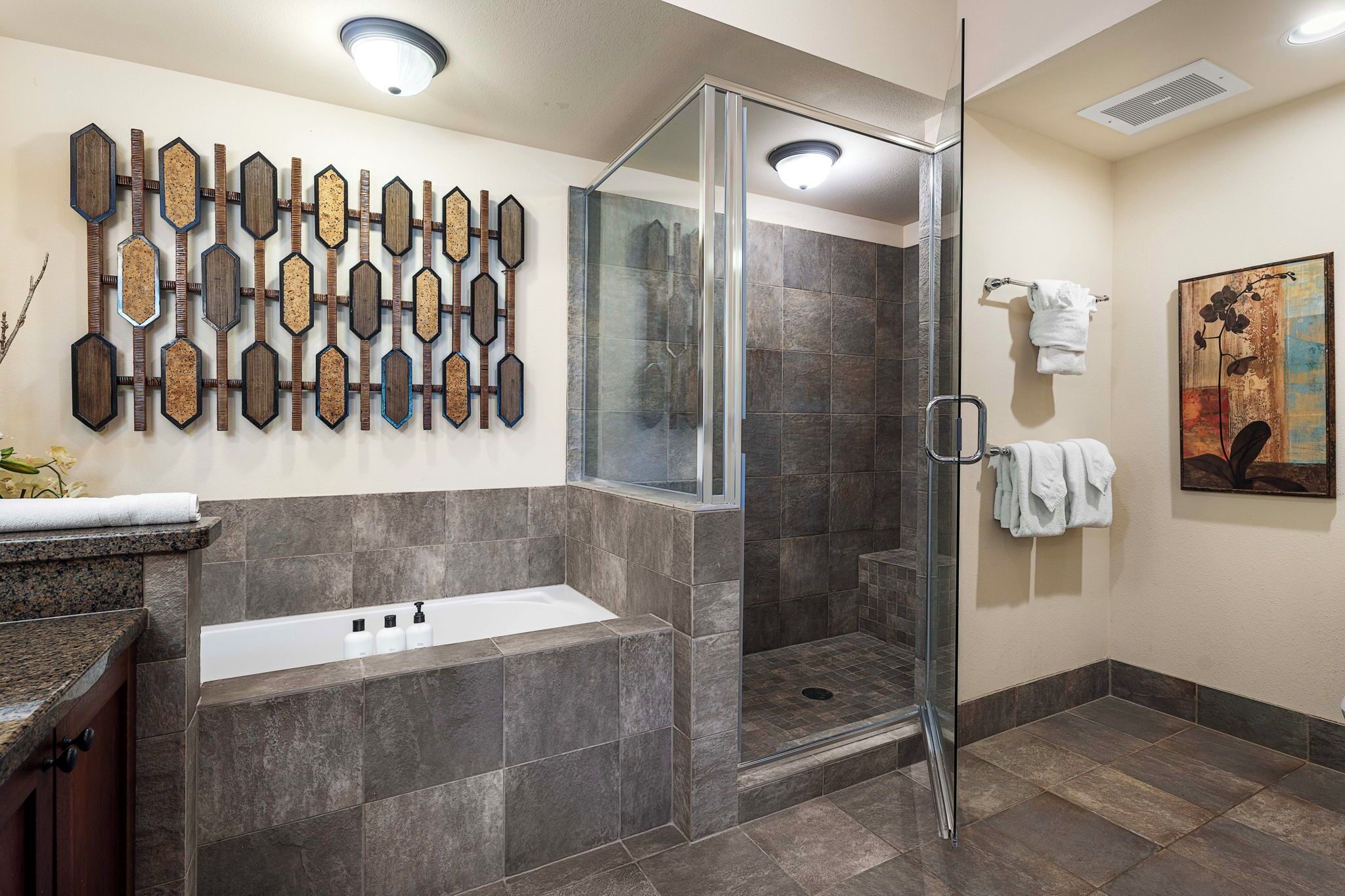 Un baño moderno con ducha de vidrio, bañera independiente y un panel decorativo en la pared.