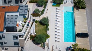 Vue aérienne d’un hôtel avec une piscine, des chaises longues et un parking.