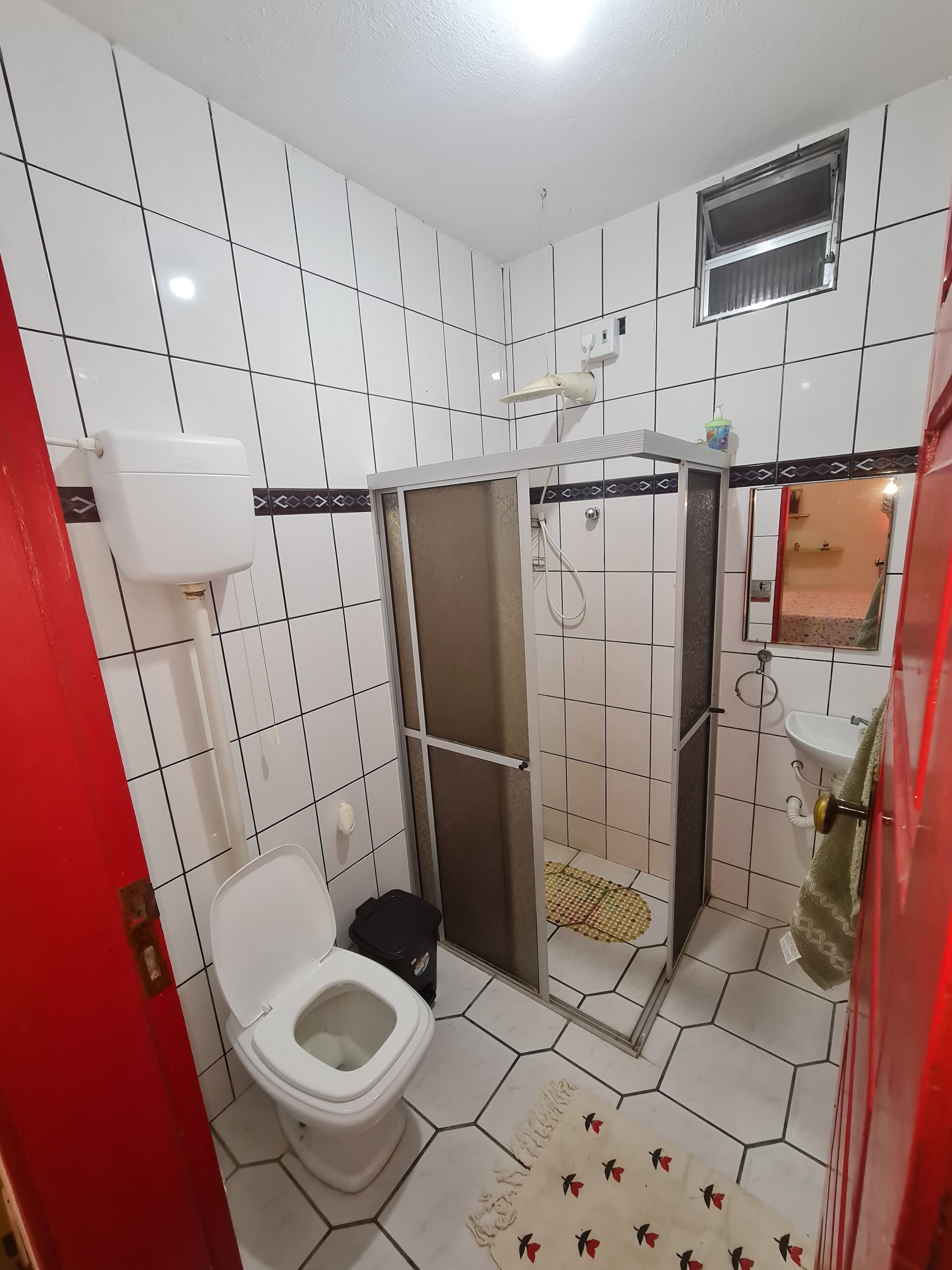 A bathroom with a toilet, shower, and sink.