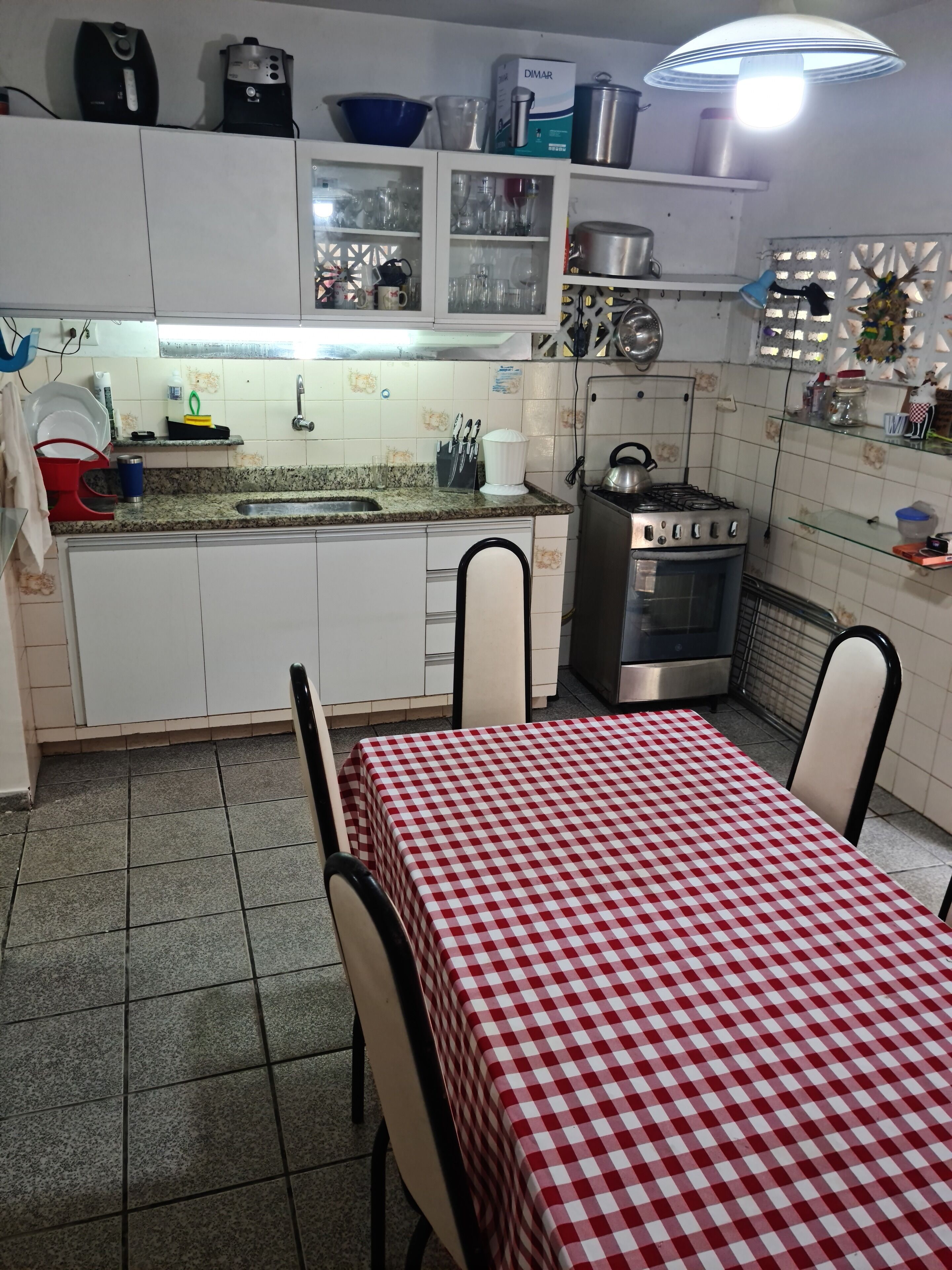 A kitchen with a granite countertop, white cabinets, a gas stove, and a checkered tablecloth.