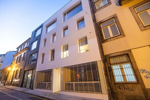 Een meerlaags gebouw in moderne bouwstijl, met een combinatie van raamformaten en een begane grond entree met een metalen poort.